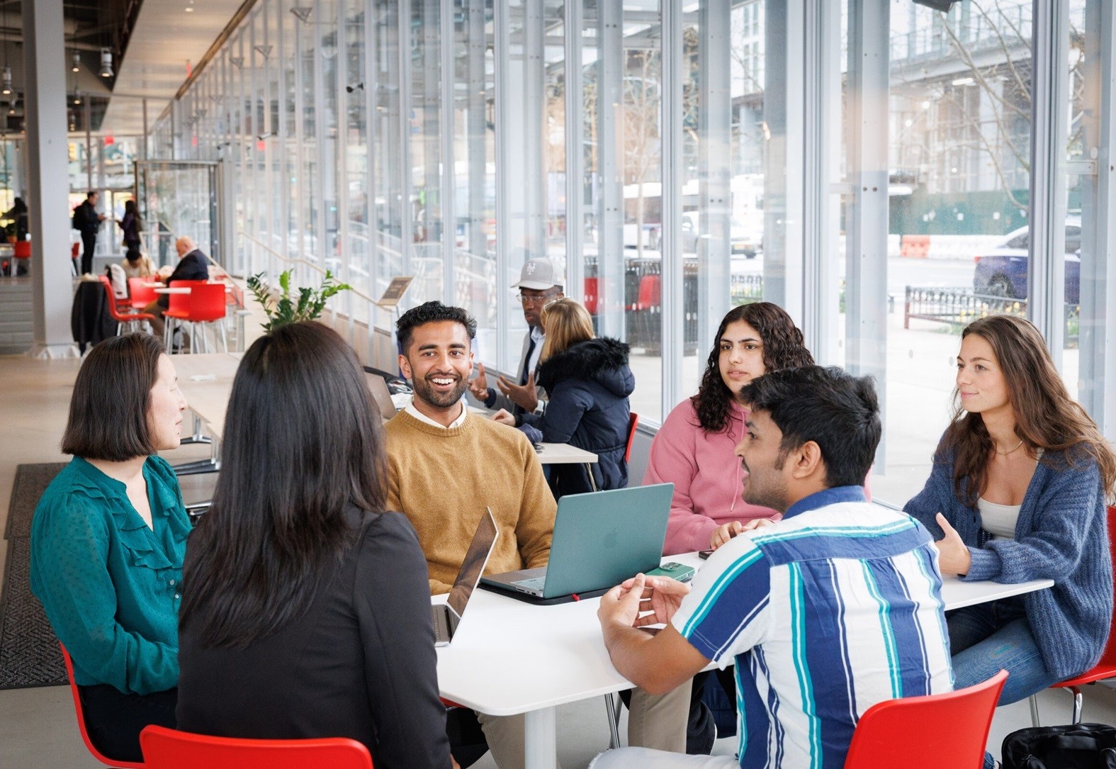 Six people sitting in a group with laptops on table